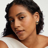 Woman wearing Seashell Studs in 18k gold vermeil, curly hair and white dress, close-up on the earrings.