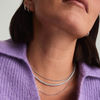 Woman wearing Lab Grown Sapphire Tennis Necklace crafted in sterling silver, with a close-up highlighting the necklace and matching silver hoop earrings.