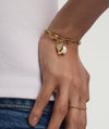 Close-up of a hand wearing the Mejuri Custom 14k Chain Bracelet Track 1, featuring a gold chain with a heart charm.