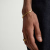 Close-up of a person's wrist wearing a Slim Cuff, a simple gold bracelet that complements any outfit.