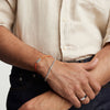 Man wearing a Bar Cord Bracelet on his wrist, shown in a close-up, highlighting its elegant design. The bracelet serves as a stylish, signature accessory.