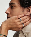 Man holding his face, showcasing a prominent Square Signet Ring on his finger.