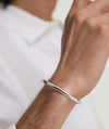 Person wearing a Slim Cuff silver bracelet on their wrist, highlighting its simple and versatile design suitable for any outfit.