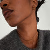 Close-up of a woman's neck wearing the Spheres Chain Necklace, a minimal gold accessory, highlighting its elegance and versatility.