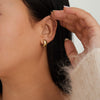 Close-up of a woman's ear adorned with Chunky Huggie Hoops, showcasing their thick design and secure clicker closure.