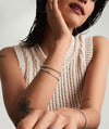 Woman touching her face, highlighting the Trace Rectangle Chain Bracelet on her wrist, showcasing its sleek, edgy, handcrafted sterling silver design.