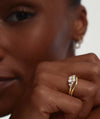 Close-up of a woman's hand wearing the Nesting Band, a gold ring, highlighting its elegant design and fit.