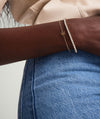 Close-up of a woman's arm wearing a handcrafted 14k solid gold Letter Bracelet, showcasing the elegant design and intricate craftsmanship.