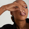 Woman with freckles holding her mouth, showcasing the Serpentine Chain Bracelet with flat, braided links for comfortable all-day wear.