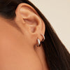 Close-up of a woman's ear adorned with Bold Huggie Hoops, showcasing their sleek, outfit-elevating design and subtle elegance.