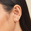 Close-up of a woman's ear wearing a Pos - Straight Lightning Bolt Flat Back Stud earring, handcrafted in 14k gold with a titanium post.