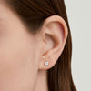 Close-up of a woman's ear wearing Round Topaz Studs in 18k gold vermeil, showcasing the handcrafted, clear-cut topaz gemstones.