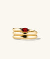 Boa Gemstone Coil Ring: a close-up of a gold ring with a prominent red oval-shaped gem, designed in an elegant coil style.