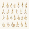 Cursive Letter Charm: A collection of gold letter pendants, each with a ring, perfect for personalizing jewelry with initials.