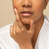 Close-up of a woman touching her chin, showcasing the Slim Signet Ring, a delicate 14k gold ring with a bezel surface, ideal for engraving.