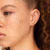 Close-up of a woman wearing Bold Sphere Studs, showcasing handcrafted 14k hollowed gold earrings that blend daintiness with boldness.