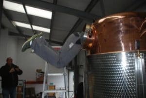 An image of a man hanging inside an alcohol still with only his legs visible