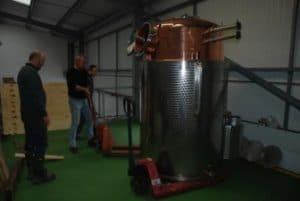 An image of a fully assembled alcohol still with two men watching on