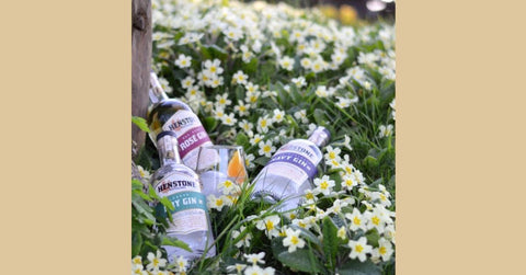 Image of 3 henstone bottles in a flower bed next to a tree