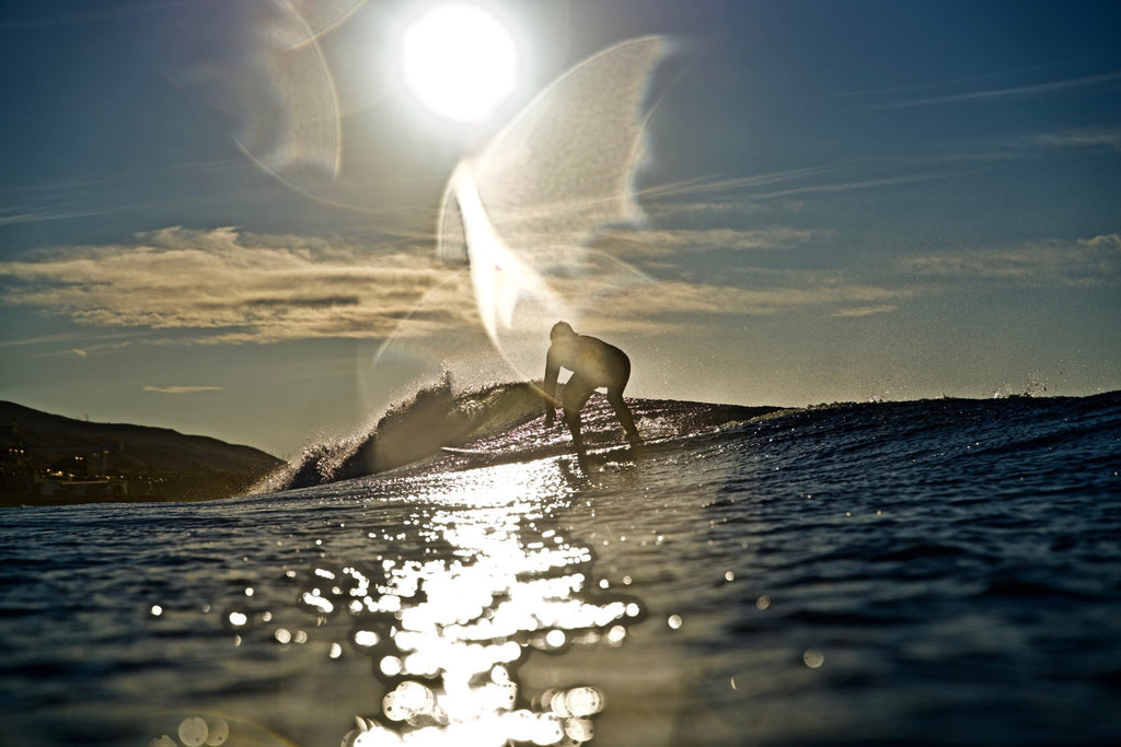 Sun glare reflected on the Outex optical glass lens port creating beautiful imaging results of surfer in the waves