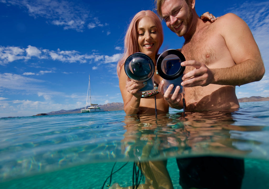 Couple regardant dans les boîtiers sous-marins de leur smartphone Outex en naviguant