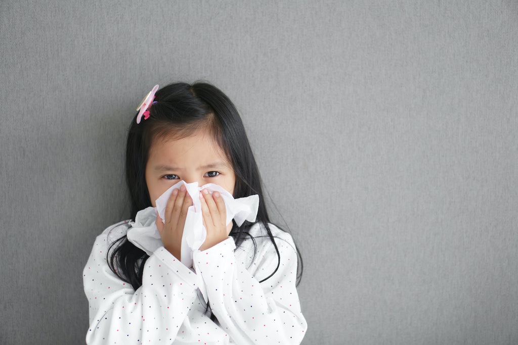 girl sneezing into a tissue on a tray background