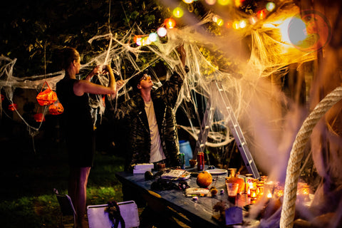 Group of friends setting up Halloween decorations in the backyard using Ravenox hemp ropes, creating an atmospheric outdoor party setting.