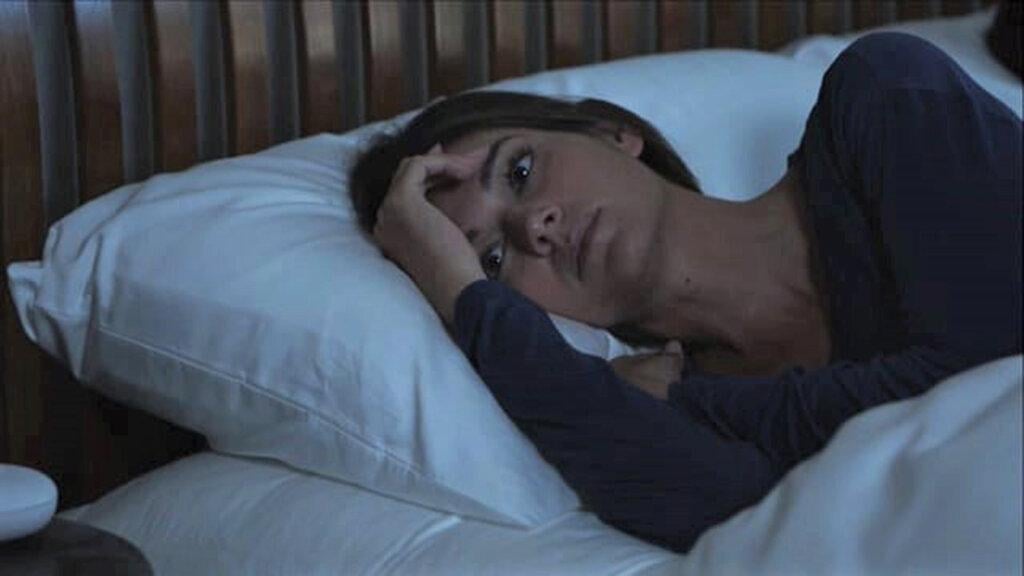 Woman lying in bed wide awake and not happy