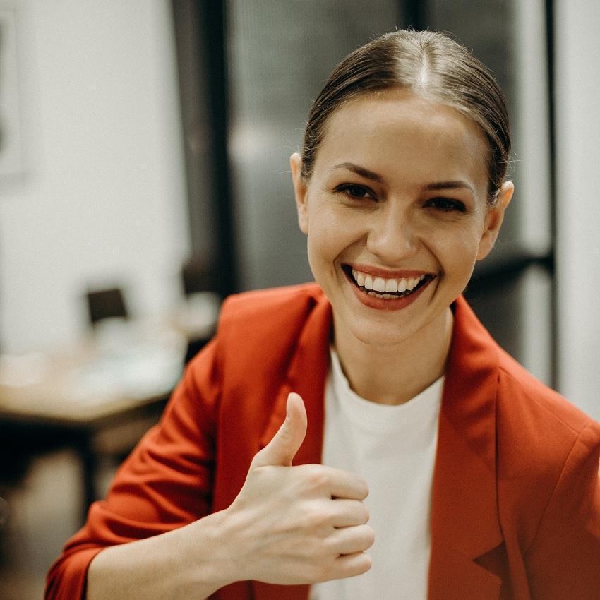 A vibrant young woman at work giving a "thumbs-up" sign. Brief naps can boost your mood and energy to help you finish your day productively.