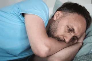 Man laying on bed has anxiety