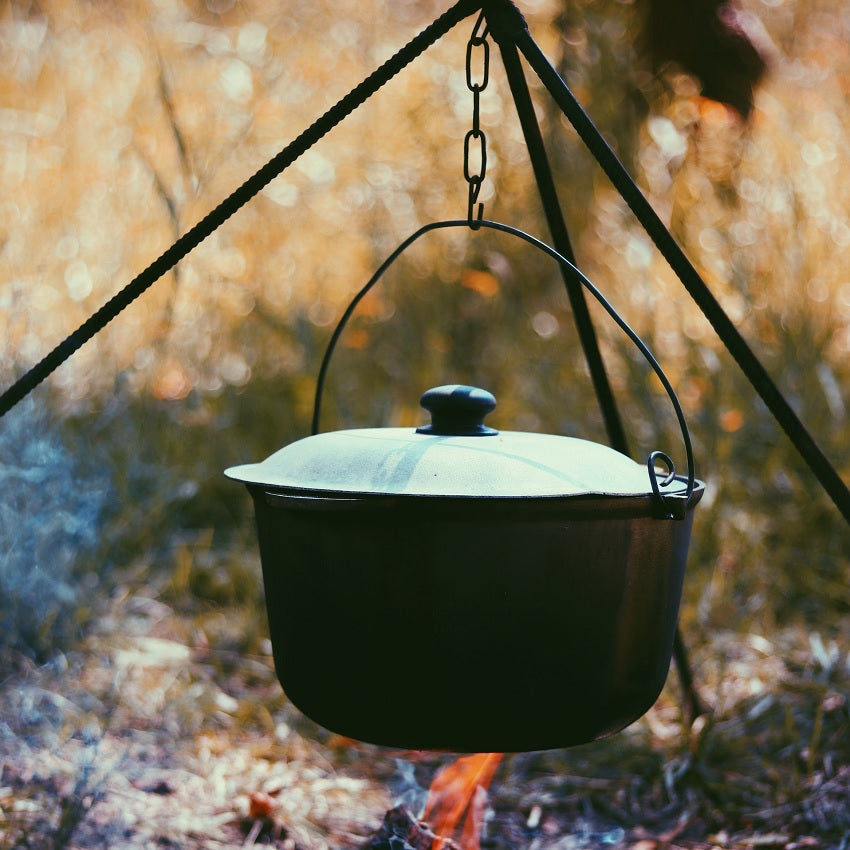 A Dutch oven hangs over an open campfire. One pot meals are great for combining different healthy food elements into a tasty meal. 