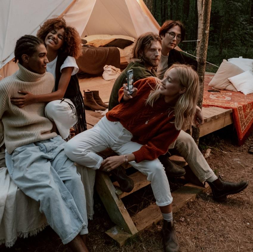 A group of friends hanging out in the evening on the front steps of a glamping tent platform.