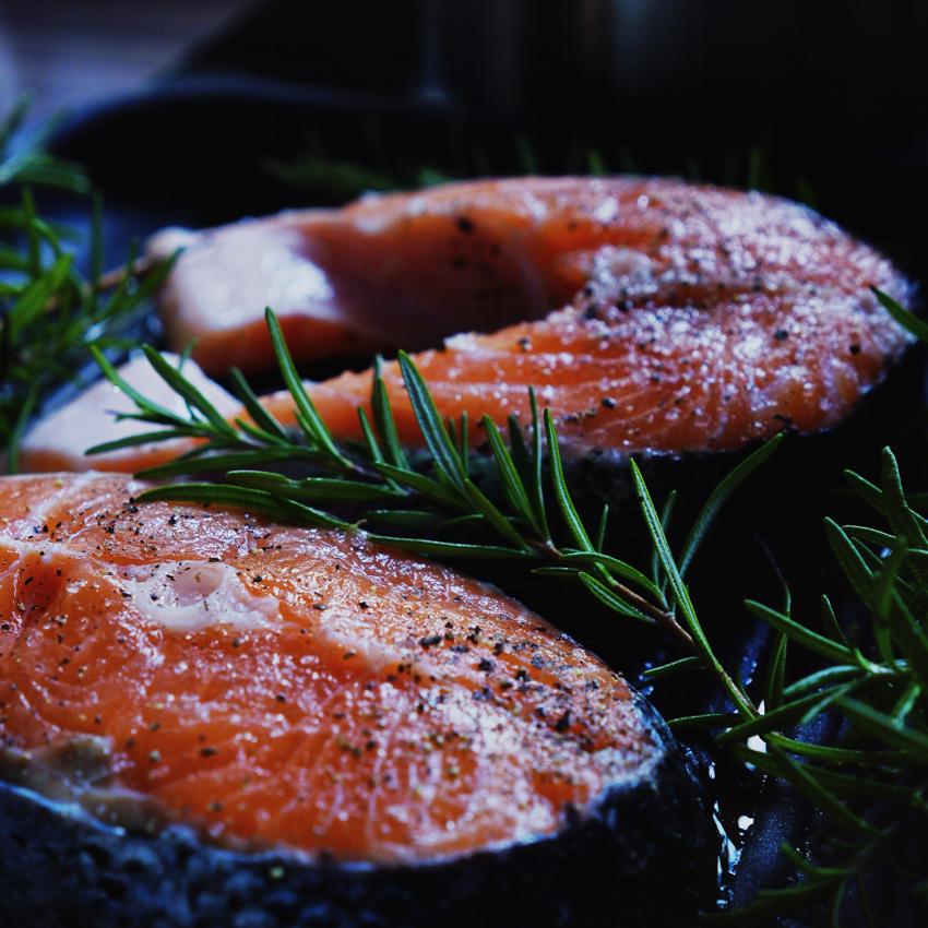 2 Salmon steaks cooking on a hot grill with Rosemary sprigs. Fish is a great source of melatonin.