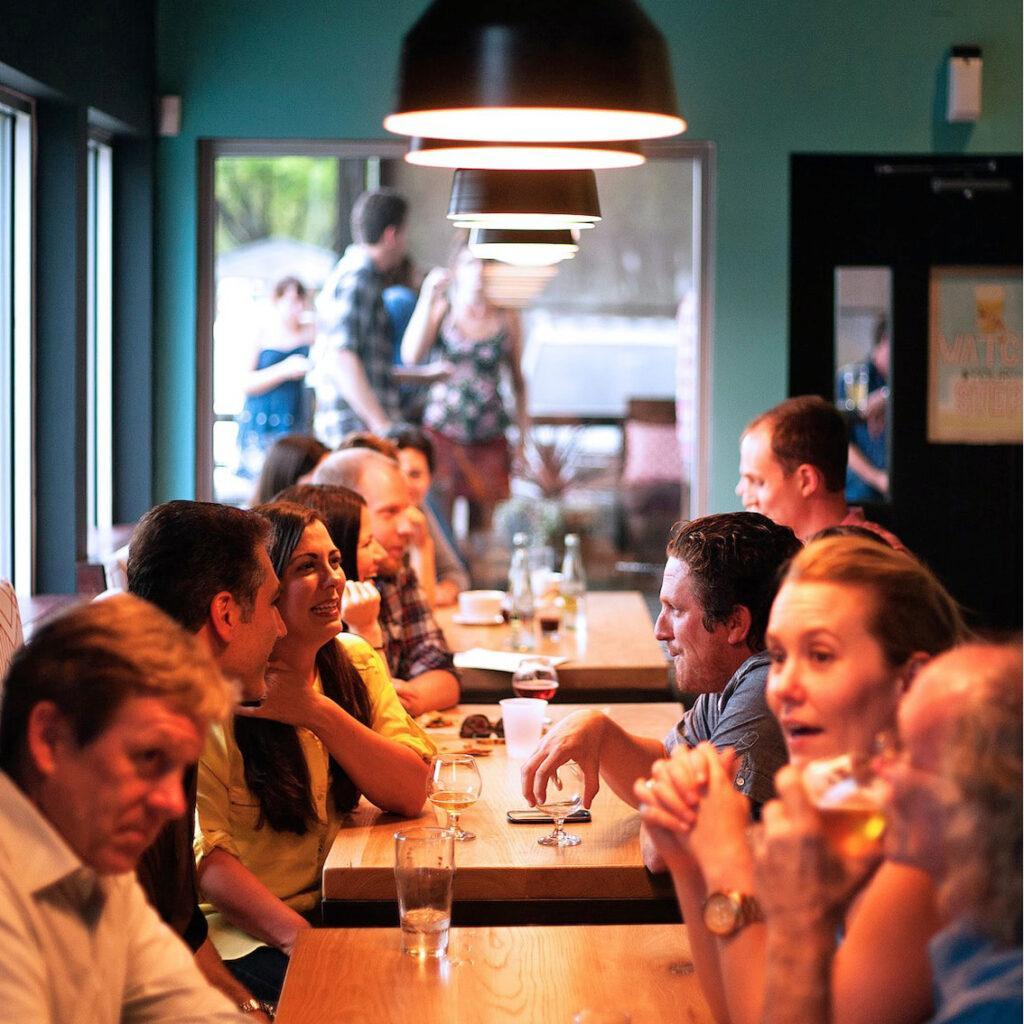 A group of people enjoy drinks in a busy restaurant. Staying connected to others wards off depression which can cause sleep problems.