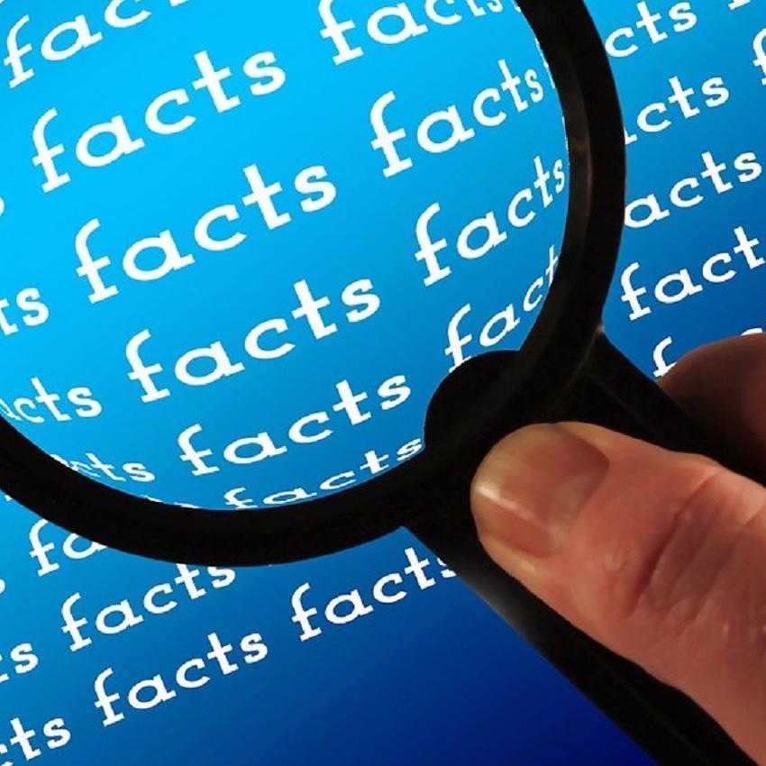 A hand holding a magnifying glass, hovers over a deep blue document with the word "facts" in white letters, repeated on every line. Fact: coffee first thing in the morning is not helpful.