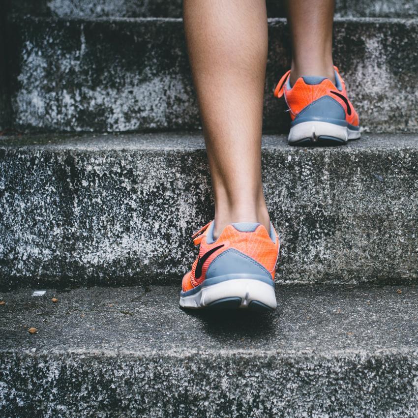 legs from the calf down, orange tennis shoes worn and running up stone stairs