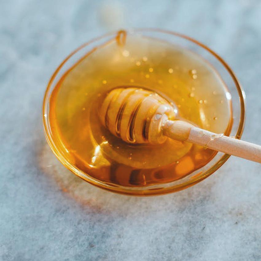 Small glass bowl of honey with dipper
