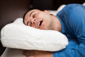 Man in blue sleeping on his side with mouth open