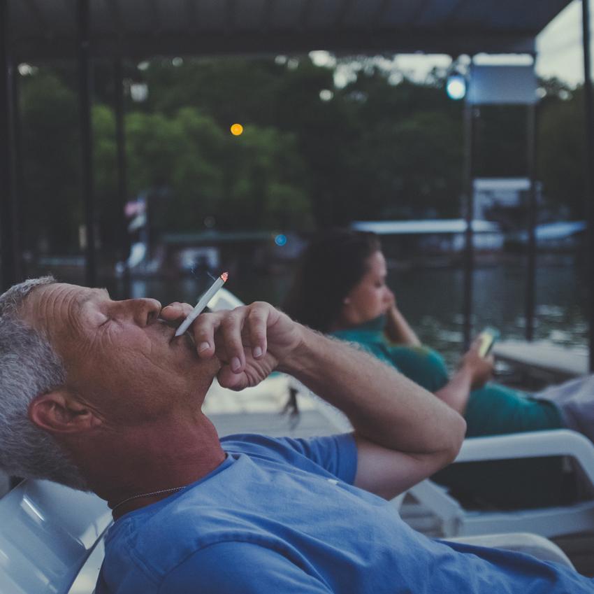 A man reclines poolside, smoking a cigarette. If you're tired of waking up all night, try not smoking before bed.