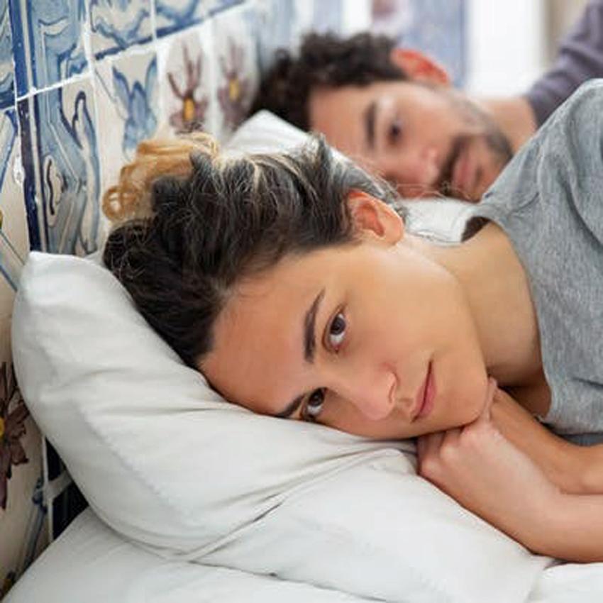 A man and woman lie awake in bed angry and not looking at each other