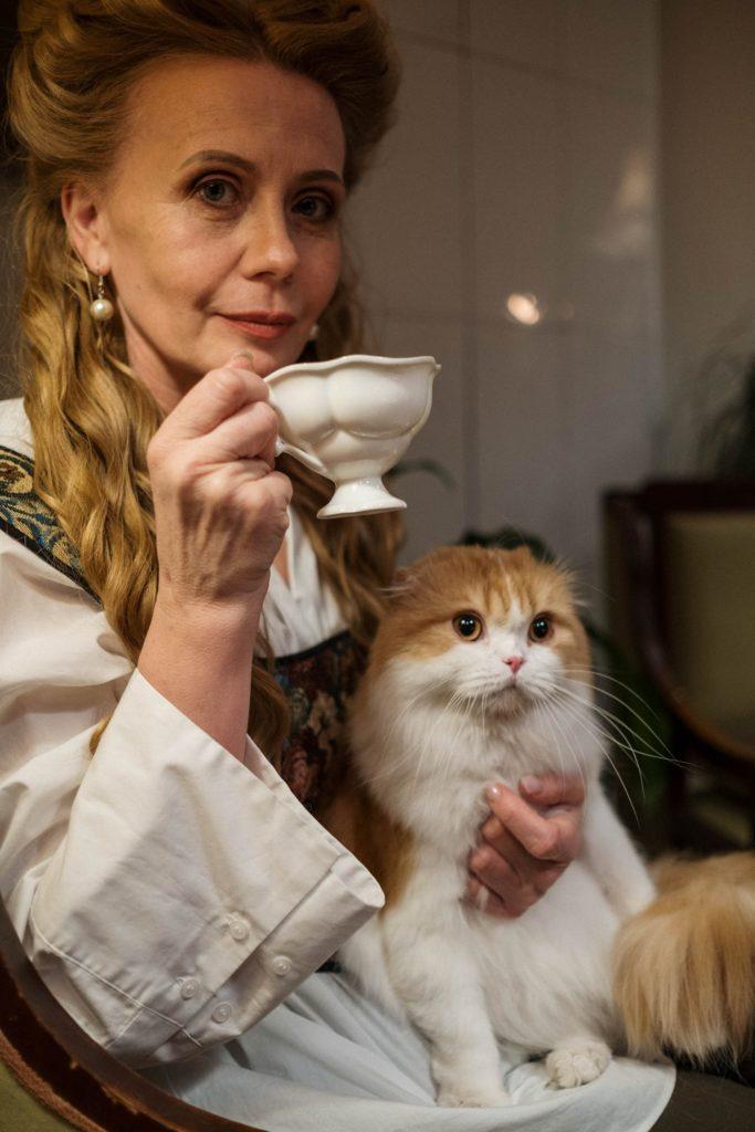 Lady holding cat, sipping tea