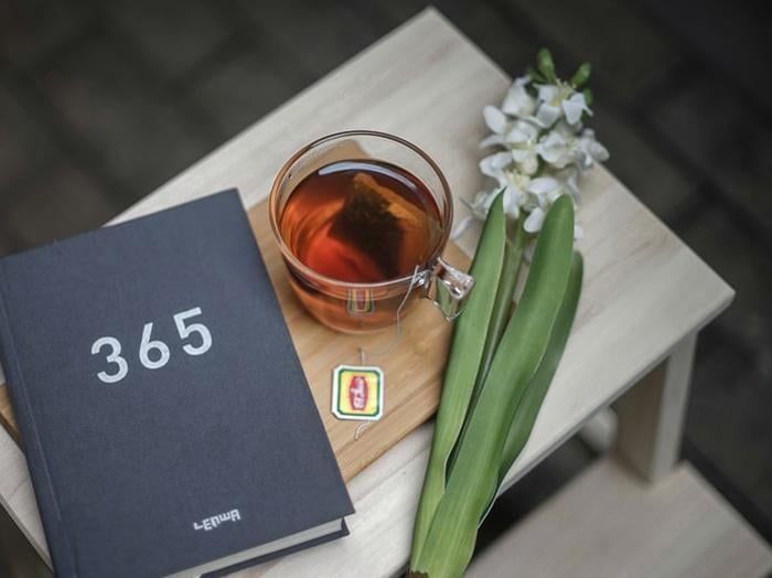 Table with journa., cup of tea and small bouquet flowers