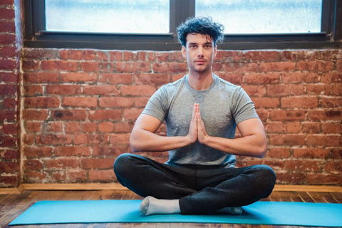 man meditating on blue yoga mat