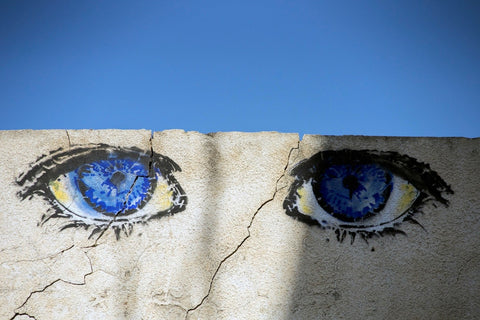 a white washed brick wall with bright blue eyes painted on it