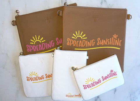 Group of bags with "Spreading Sunshine" printed on them with yellow and hot pink writing