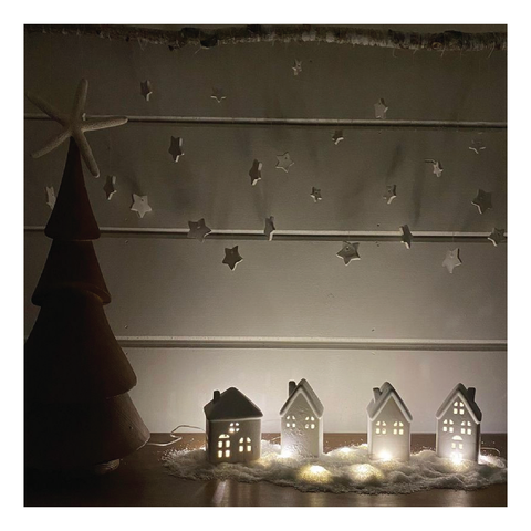 Four tiny white houses lit by fairy lights for the Holiday display.