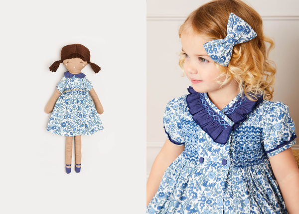 A headshot of a young blonde girl wearing the Daphne dress with a matching bow in her hair. To the left, there is an ecommerce image of the Daphne doll.
