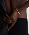 A person wearing a Slim Cuff, showcased on a wrist with a gold ring and bracelet.