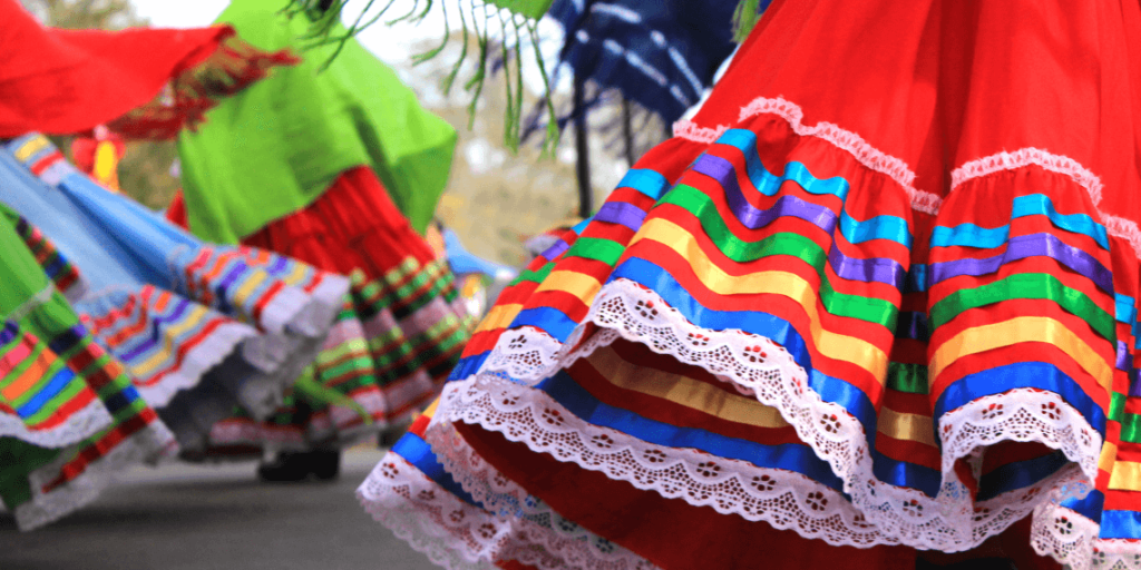 Colorful Mexican-style skirts twirling during the San Juan Swallows Day Parade, a vibrant celebration of culture and tradition.