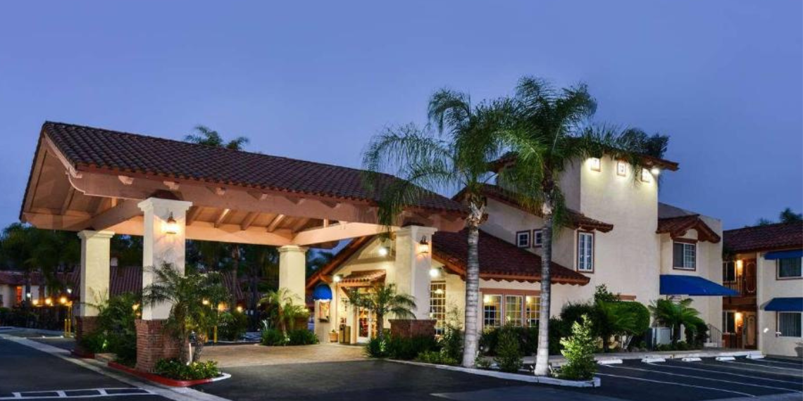 Exterior view of Best Western Capistrano Inn, with warm, welcoming lights illuminating the budget hotel's lobby at dusk, indicating that the hotel is open and ready to receive guests.